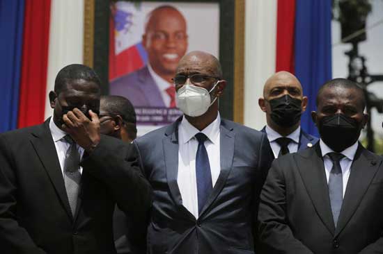  In this July 20, 2021 file photo, Haiti's designated Prime Minister Ariel Henry, center, and interim Prime Minister Claude Joseph, right, pose for a group photo with other authorities in front of a portrait of slain Haitian President Jovenel Moise at the National Pantheon Museum during a memorial service for Moise in Port-au-Prince, Haiti. Haiti’s chief prosecutor has asked a judge to charge Henry in the slaying of his predecessor and barred him from leaving the country. (AP Photo/Joseph Odelyn, File)