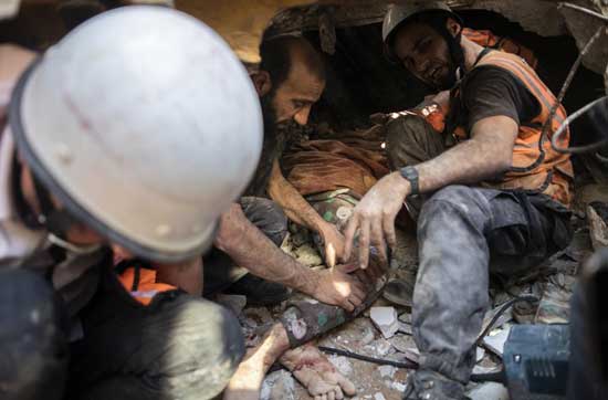 Palestinian rescuers pull the body of a woman from under the rubble of a destroyed residential building following deadly Israeli airstrikes on Gaza City that flattened three buildings and killed at least 26 people, in Gaza City, Sunday, May 16, 2021. (AP Photo/Khalil Hamra)